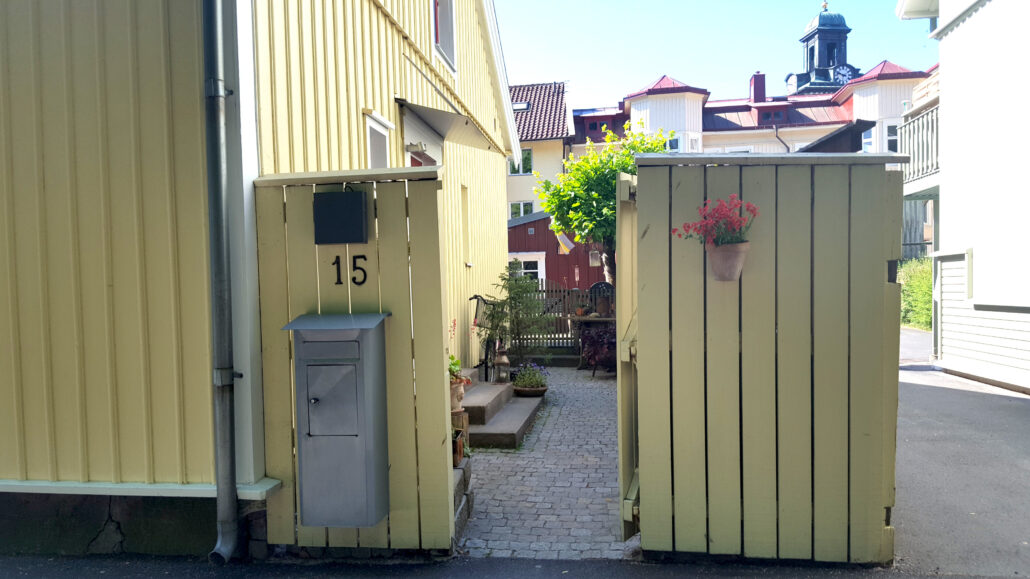 Gult trähus med staket och en öppen grind längs med Norra Ringgatan i Alingsås.