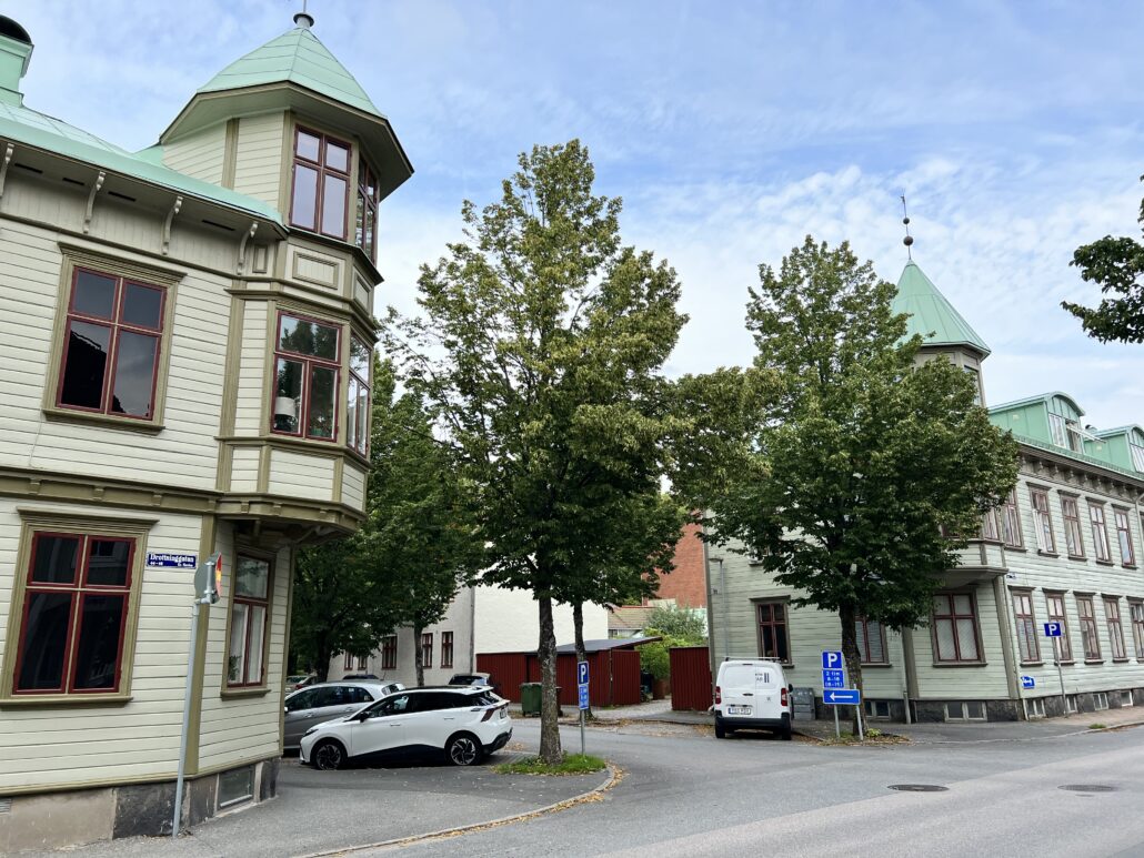 Ljusgrönt trähus med torn på Alströmergatan i Alingsås stadskärna med en allé.