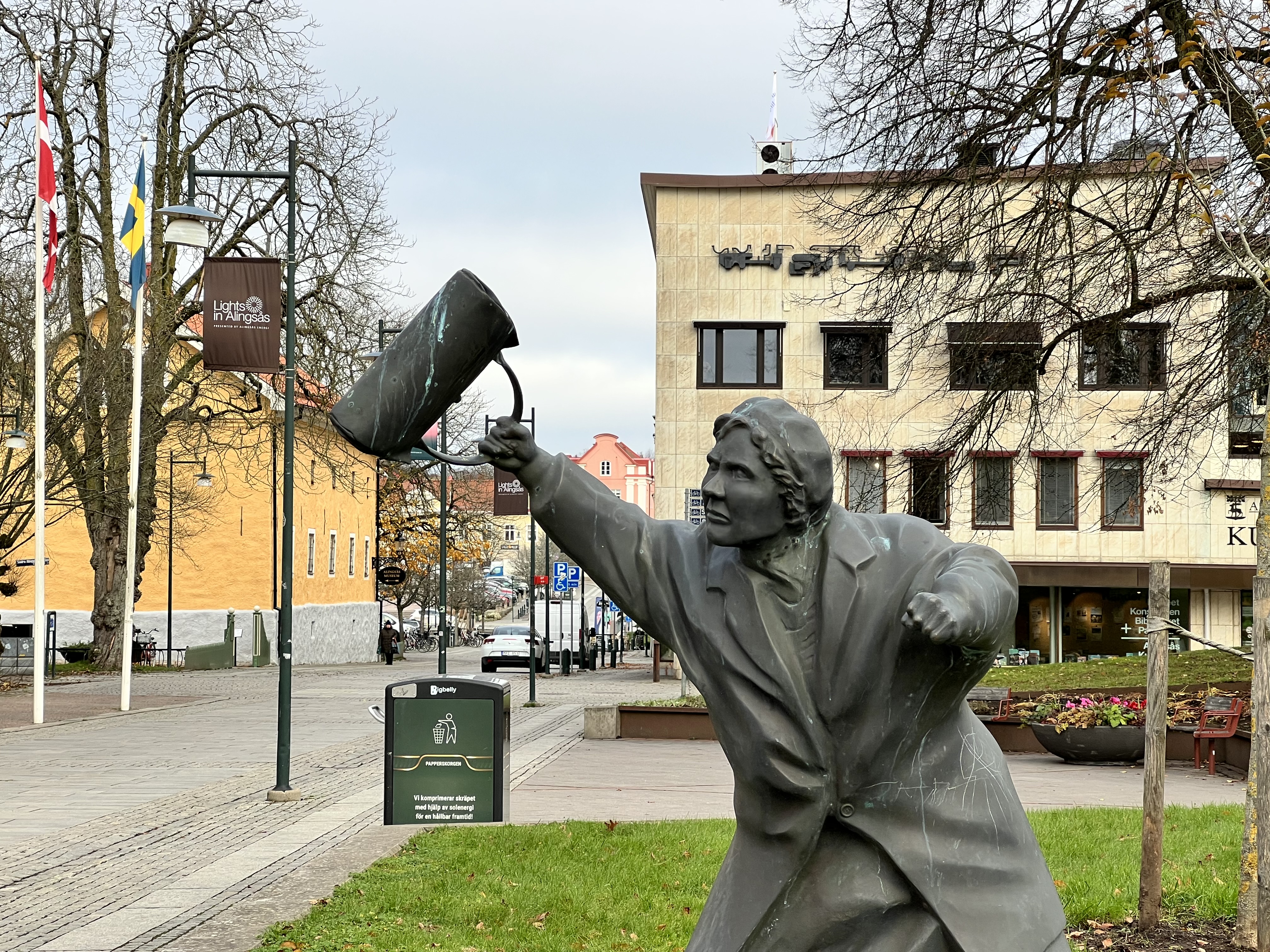 Med handväskan som vapen. Skulptur av Susanna Arwin i Alingsås stadskärna i Åmanska parken framför Grand Hotel Alingsås.